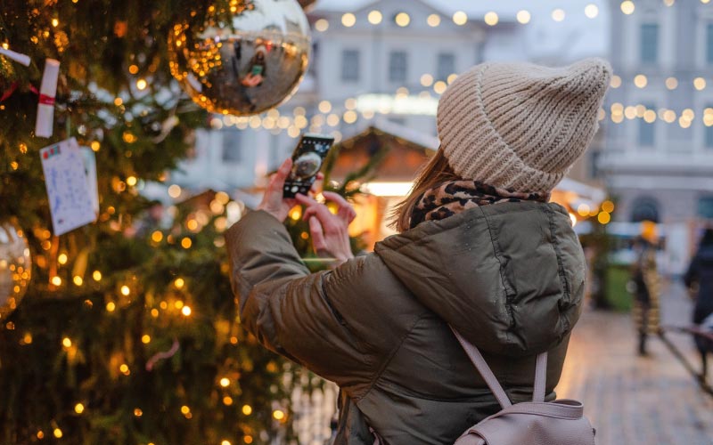 Femme prenant une photo d'un sapin sur un marche de noel
